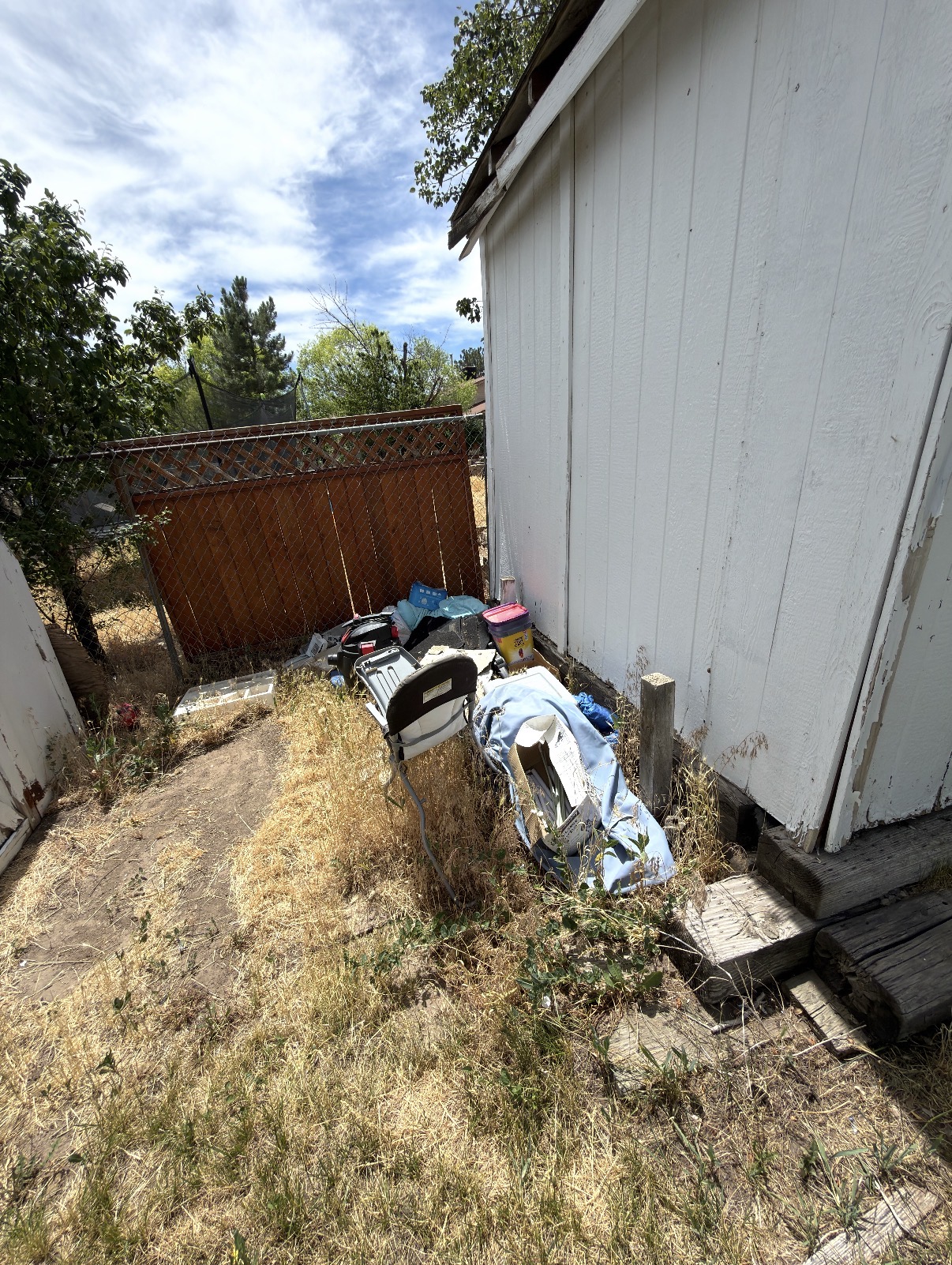 Cluttered backyard full of junk and debris before clean-out in Salt Lake County
